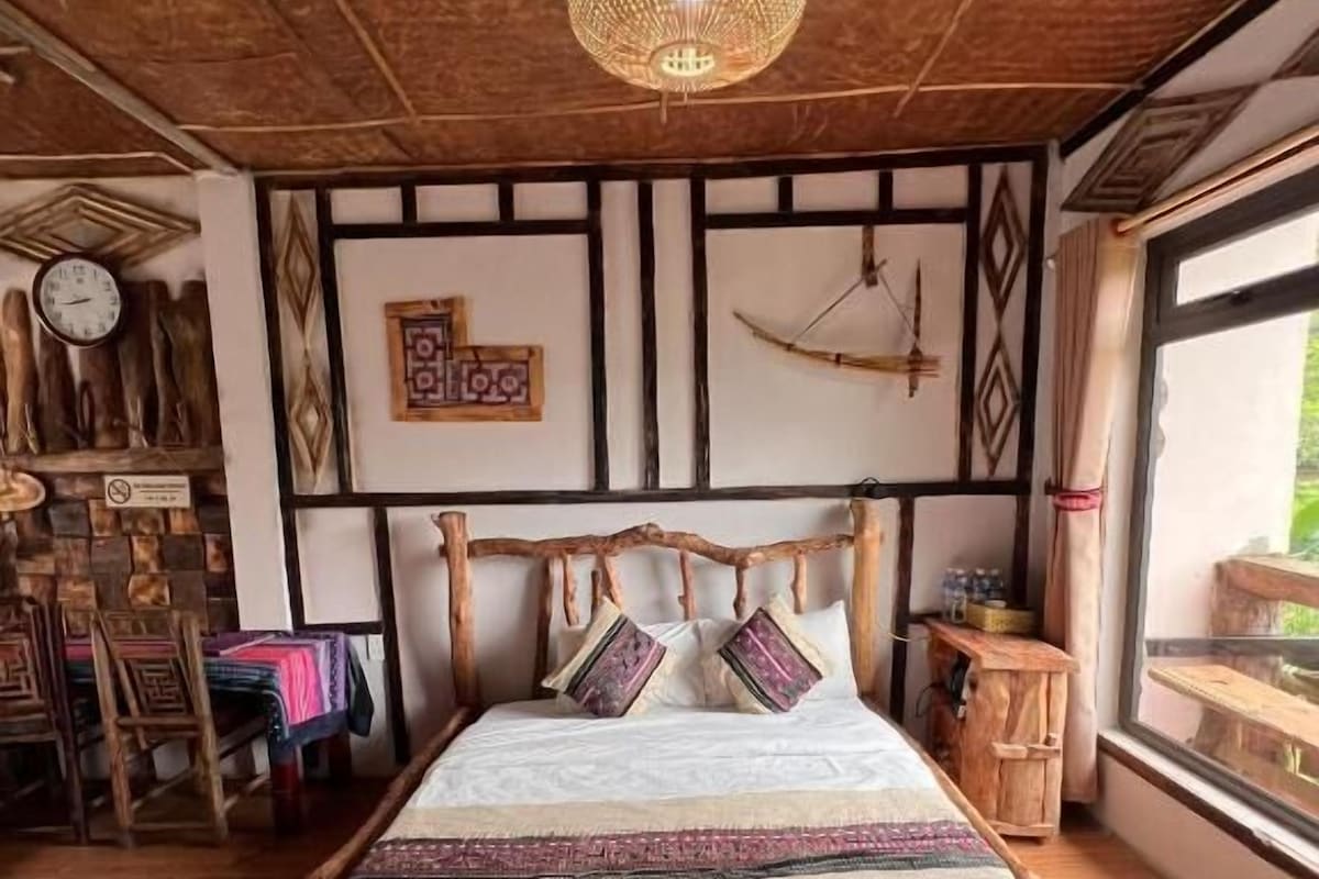 Una habitación rústica con una cama, muebles de madera, una lámpara colgante y una ventana con vistas.