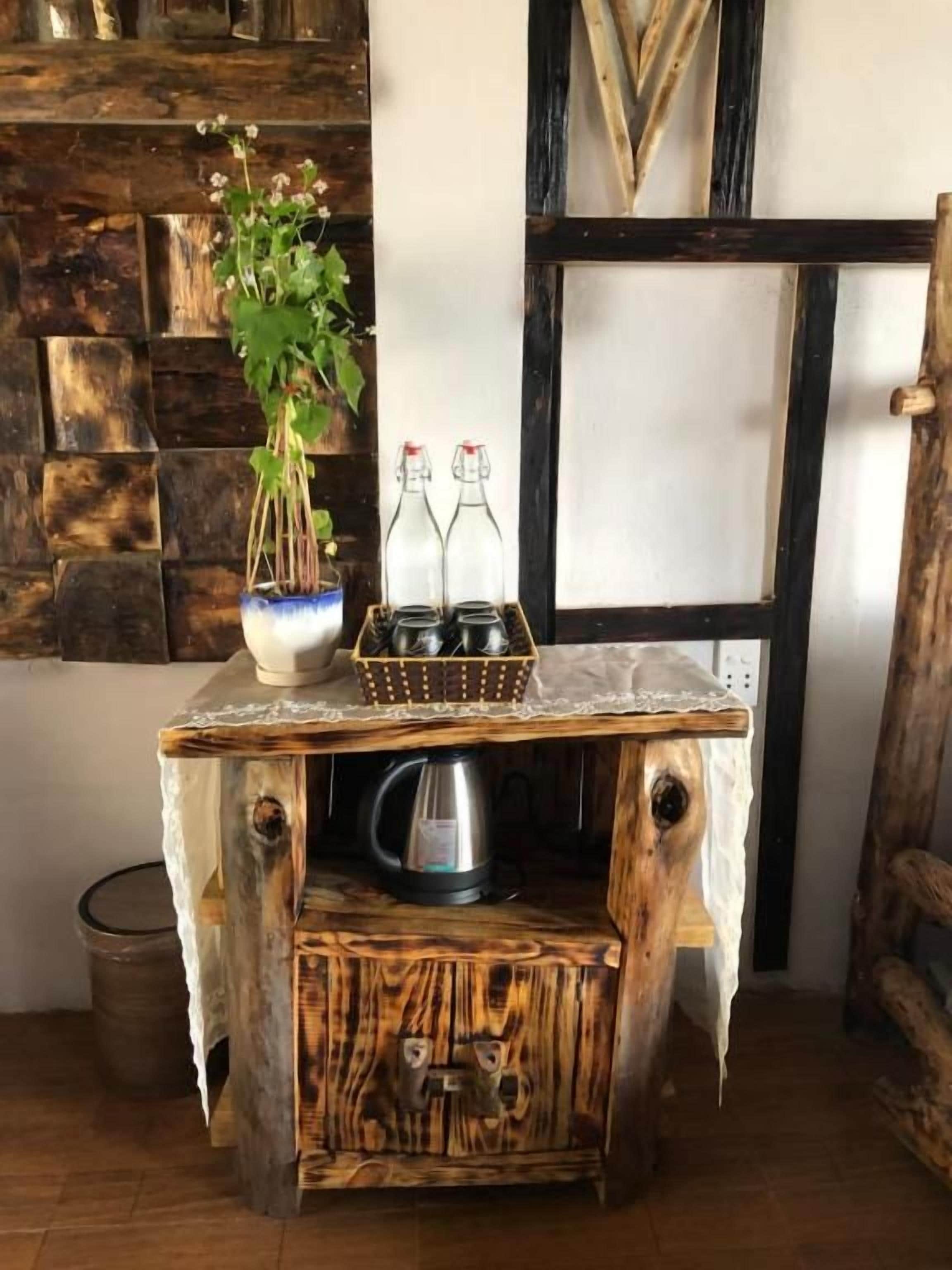A rustic wooden table with a kettle and a vase of flowers.