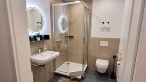 Un bagno moderno con doccia vetro, lavabo e water.