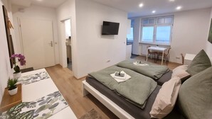 Una camera da letto moderna con due letti, una scrivania e una TV.