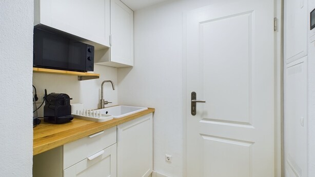 Une petite cuisine équipée comprenant un four à micro-ondes, un évier et un plan de travail en bois.