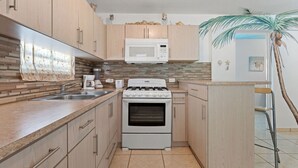 Une cuisine de taille réduite, dotée de meubles en bois, d’un four à micro-ondes, d’une cuisinière et d’un évier.