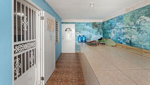 Un couloir avec un mur bleu, une porte blanche et un sol carrelé.