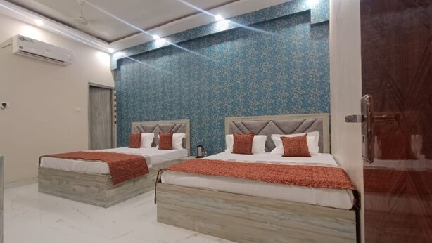 A hotel room with two beds, each with a wooden headboard and red bedding. - Vrrinda By GRB (Varanasi)