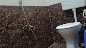 A bathroom with a toilet, a shower, and a marble floor. - Vrrinda By GRB (Varanasi)