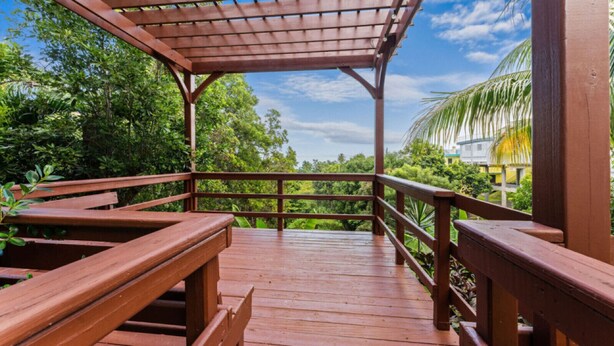 A wooden deck with benches, surrounded by lush greenery and a clear sky. - Casita 4 at Ceiba Tree Inn (Rincón)