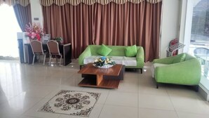 Un salon avec un canapé vert, une table basse en bois et un tapis à motifs.