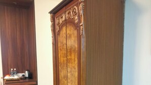 Une chambre avec une armoire en bois, un petit réfrigérateur et un banc en bois.