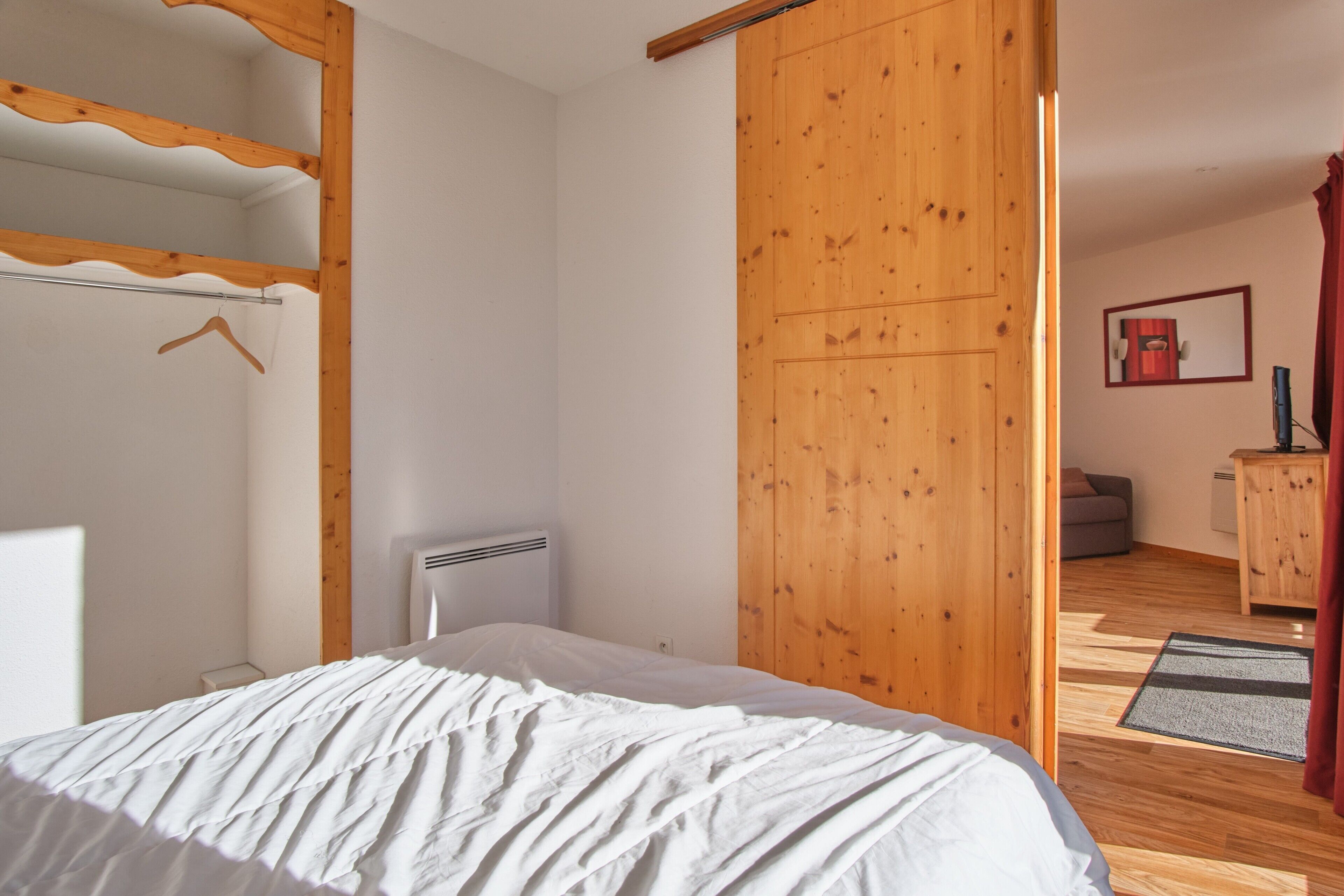 Une chambre à coucher comprenant un lit, une armoire en bois et un petit coin salon avec un canapé et une table.