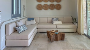 Una sala de estar moderna con un sofá seccional color beige, una mesa de centro de madera y decoración mural tejida.