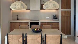 Una cocina moderna con una isla central, luces colgantes y armarios de madera.