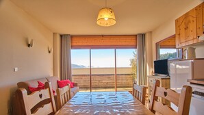 Ein Holzespeisetisch mit Stühlen, einem Fernseher und einem Kühlschrank in einem Raum mit einem großen Fenster.