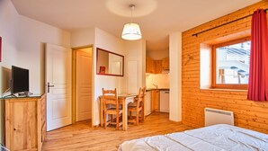 Une chambre à coucher avec un lit, un bureau avec des chaises, une télévision et une fenêtre avec des rideaux.