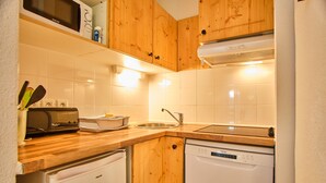 Une cuisine avec des meubles de rangement en bois, un lave-vaisselle, un four à micro-ondes et un évier.