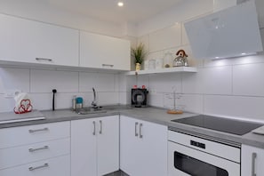 A modern kitchen with white cabinets, a built-in oven, and a stainless steel range hood. - Vacation Studio 'Loft Cerca Del Mar Tenerife' with Shared Terrace, Shared Garden and Wi-Fi (Punta del Hidalgo)