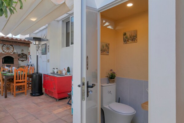 An open doorway to a bathroom with a toilet, a small potted plant, and a wall-mounted picture.