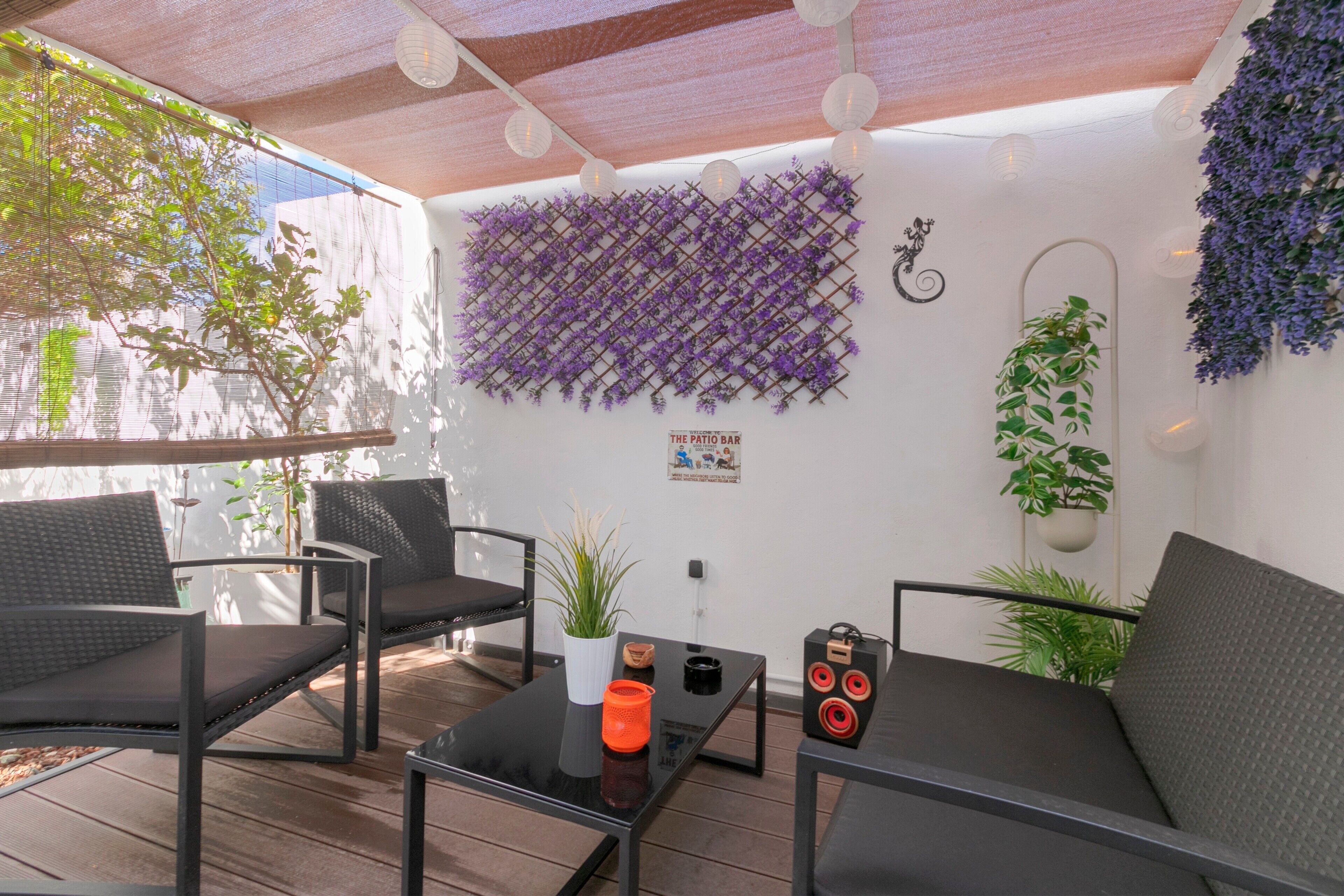 Eine Terrasse mit Sitzgelegenheiten im Freien, einem Tisch mit Kerze und Zierpflanzen.