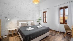 Una camera d'albergo moderna con un grande letto, un comodino, una lampada da terra e una finestra con tende.