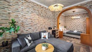 Un soggiorno moderno con un divano grigio, un tavolino rotondo in legno e una parete con decorazione a mattoni.