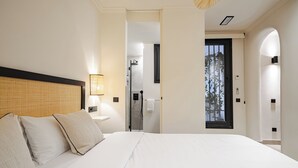 A hotel room with a large bed, a bedside table, a lamp, and a view of the bathroom. - Luxurious studio in the heart of Madrid - ST 3 (Madrid)
