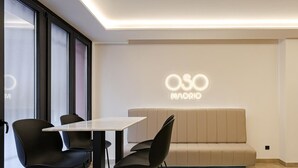 A modern interior with a sofa, chairs, a table, and a wall with 'OSO MADRID' illuminated signage. - Luxurious studio in the heart of Madrid - ST 3 (Madrid)