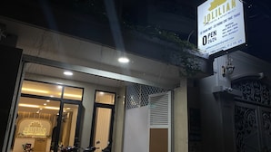 A hotel entrance with a reception desk, a signboard with contact information, and parked motorcycles. - Jolilian Hotel & Apartment (Ho Chi Minh City)