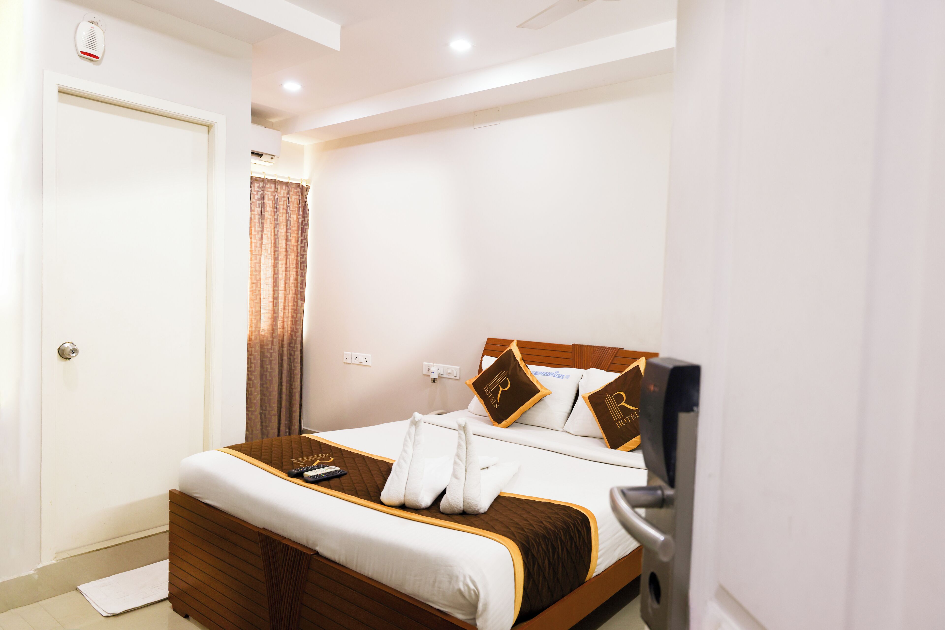 Habitación de hotel con cama, televisor, puerta y aire acondicionado.
