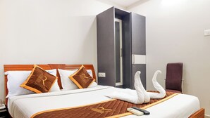 Una habitació d'hotel amb un llit, un armari, una cadira i un comandament aeri sobre el llit.