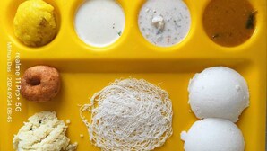 Un plat groc amb diferents plats de la cuina índia, com ara idli, vada i sambar.