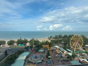 An amusement park with a Ferris wheel, rides, and a beach in the background.