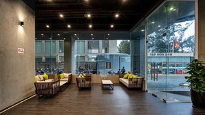 A modern lobby with seating areas, a coffee shop, and large windows offering views of the street. - Oasky Apartment Vung Tau (Ho Chi Minh City)