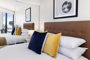 Quarto de hotel com uma cama grande, vista para a cidade e uma obra de arte emoldurada na parede.