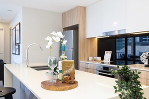 A modern kitchen with a white countertop, a wine bottle, a glass, and a Lindor chocolate bar.