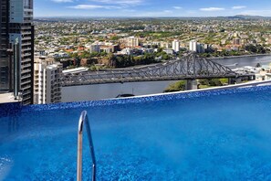 Piscina no terraço com vista para a paisagem urbana e uma ponte.
