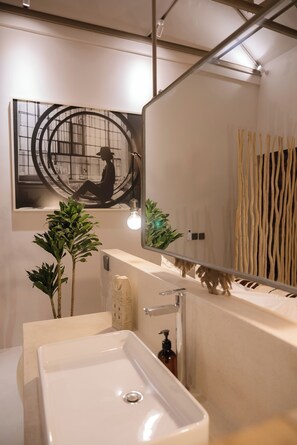 Une salle de bain moderne avec un grand miroir, deux vasques et une plante en pot.