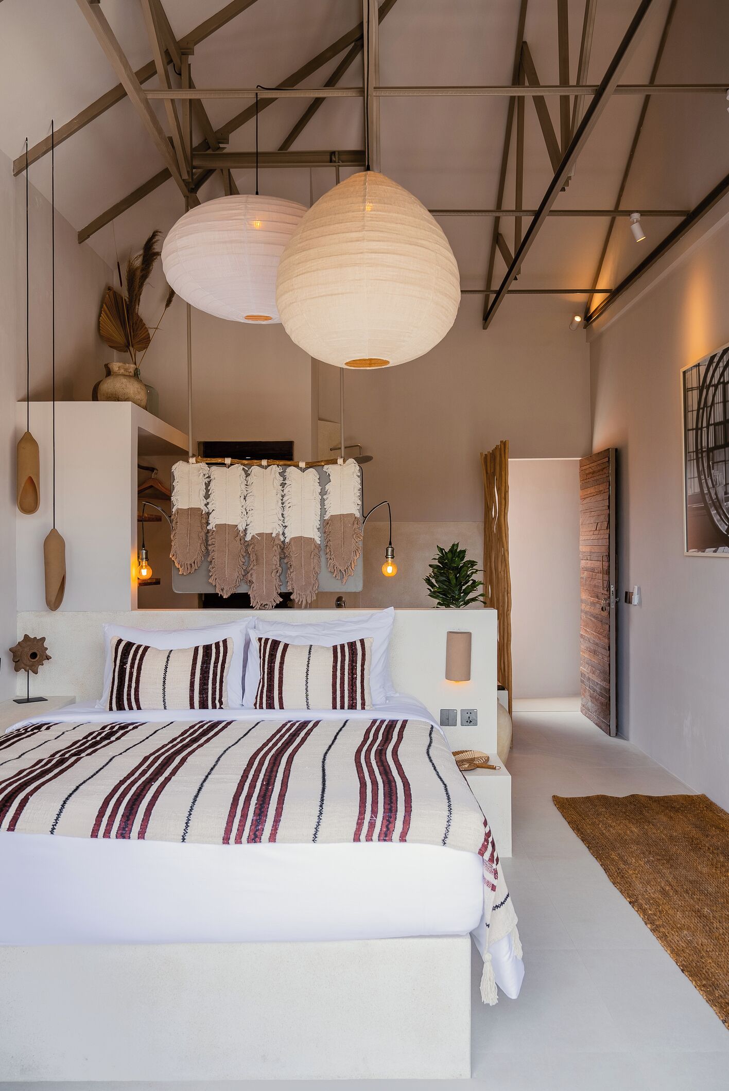 A modern bedroom with a large bed, hanging paper lanterns, and a minimalist design.