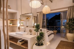 Une chambre à coucher moderne avec une grande fenêtre, une table de chevet, un miroir, une plante sur la table de chevet et un luminaire suspendu.