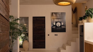 A modern interior with a large woven light fixture, a dark wooden door, a framed artwork, and a staircase. - A.K.A House Of Yin & Yang Canggu (Canggu)