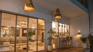 A modern interior with a wooden deck, large windows, and a bar area. - A.K.A House Of Yin & Yang Canggu (Canggu)