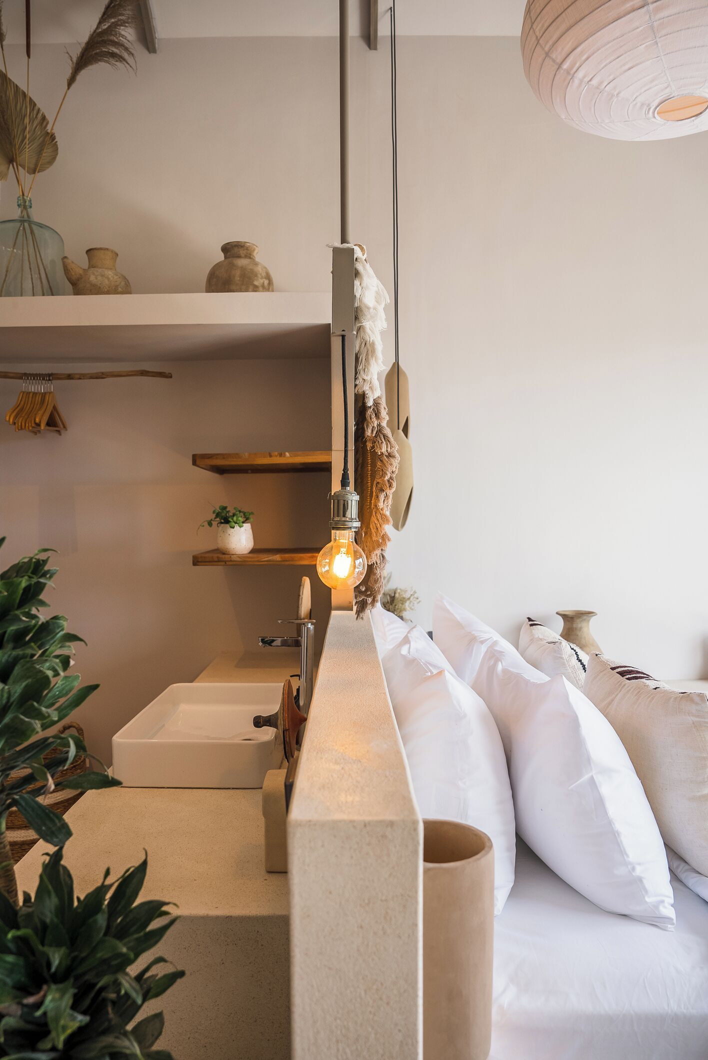 A modern bedroom with a bed, bedside tables, and a hanging light fixture.