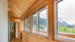 A corridor with wooden paneling and large windows offering a mountain view. - Apartment Cafe Max 2 with balcony 55 m2 (Trins)