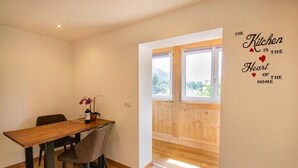 A dining area with a wooden table and chairs, a small vase with flowers, and a window with a view of mountains. - Apartment Cafe Max 2 with balcony 55 m2 (Trins)