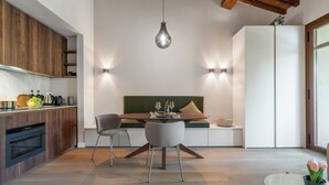 A modern kitchen with wooden cabinets, a dining area with a round table, and a built-in bench. - Correggiolo Romantic Apartment Pool Montaione Toscana (Montaione)
