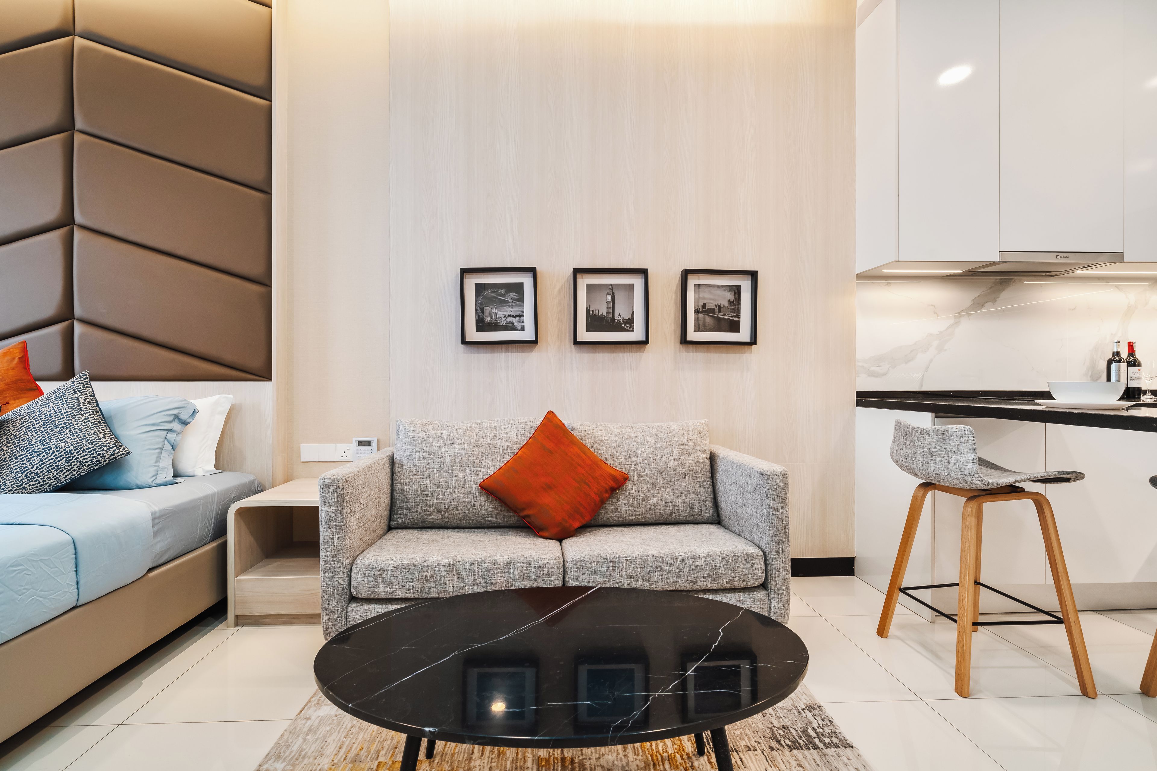 A modern living room with a sofa, a coffee table, and a kitchen area with a counter and stools.
