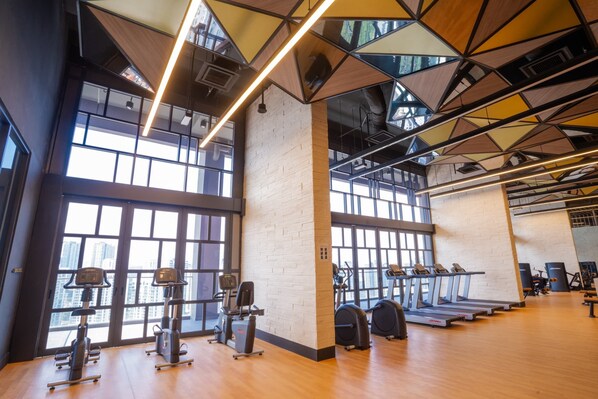 A gym with exercise equipment, large windows, and a modern ceiling design. - Societe Hartamas (Kuala Lumpur)
