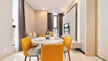 Un espace repas moderne avec une table ronde, quatre chaises jaunes et un canapé en arrière-plan.