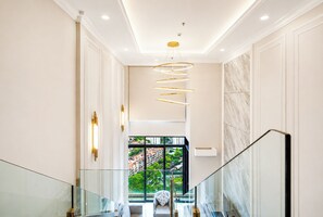 A modern interior with a glass railing staircase, a spiral light fixture, and a view of greenery outside. - Societe Hartamas (Kuala Lumpur)