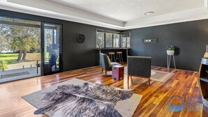A modern living room with a large glass door leading to a garden, wooden flooring, and a mix of seating options including a sofa and chairs.