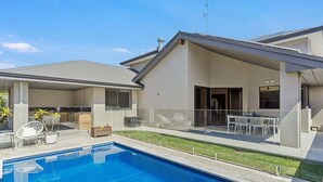 A modern house with a swimming pool, a covered patio, and a dining area.