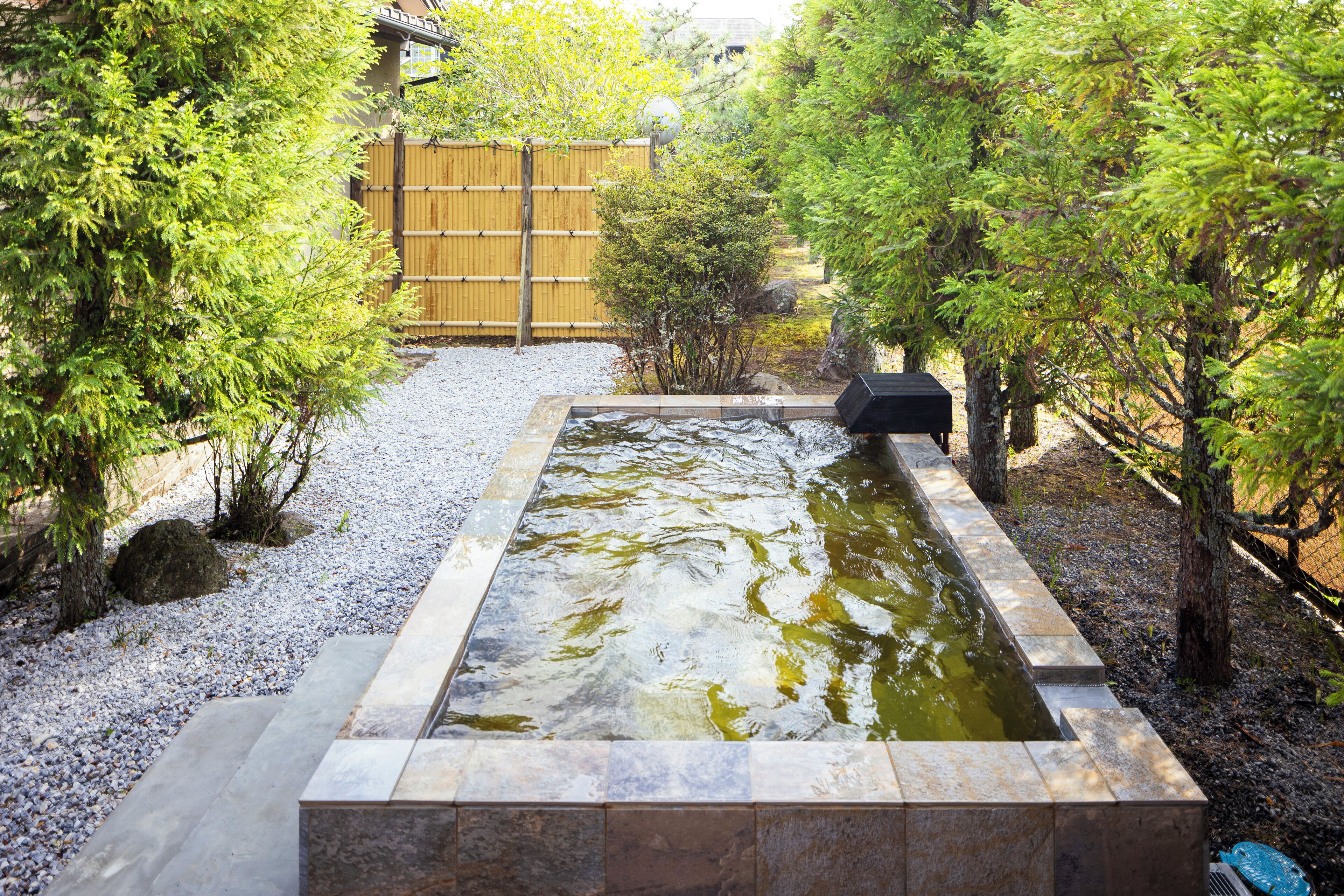 A rectangular stone pond with a wooden fence in the background.